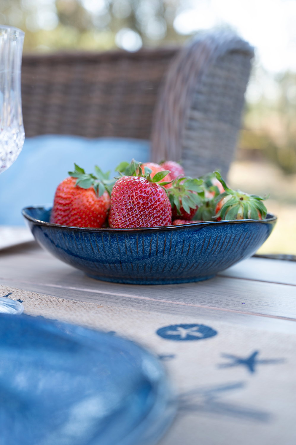 Dunkelblauer tiefer Teller mit Erdbeeren auf einem Gartentisch